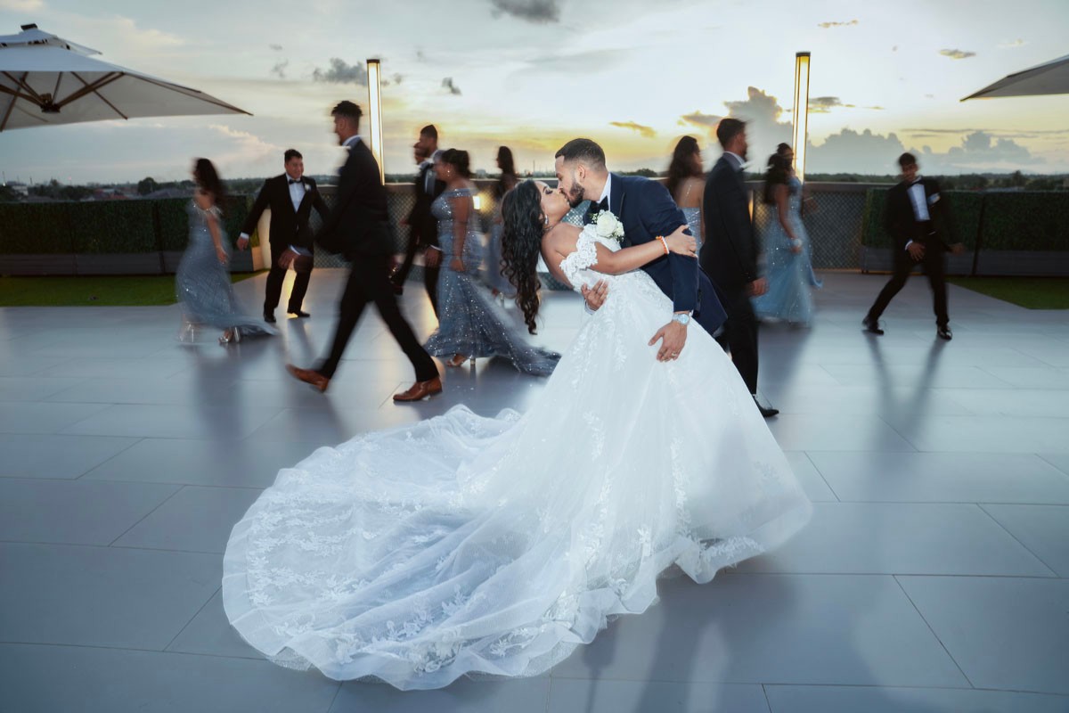 Wedding couple dancing while guests celebrate behind them