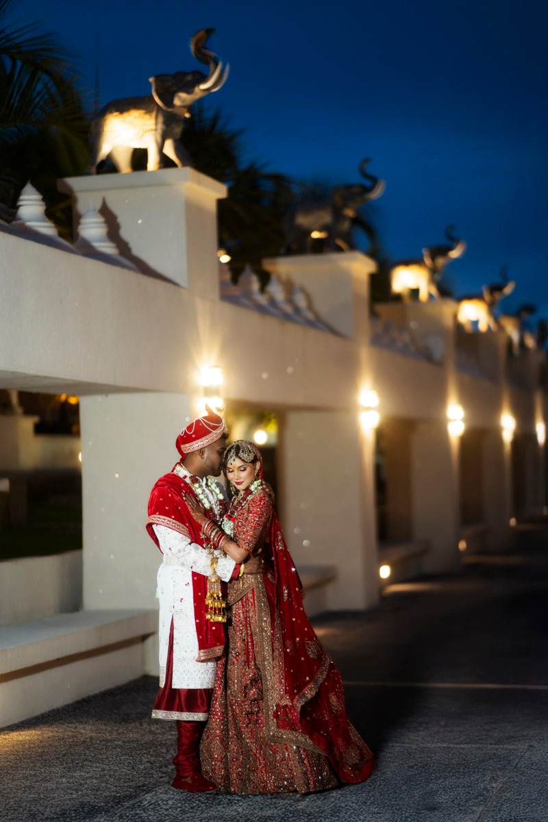 Hindu wedding couple photographed beneath illuminated elephant sculptures
